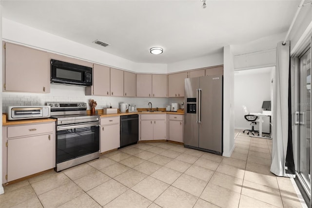 kitchen with black appliances, decorative backsplash, light tile patterned floors, and sink