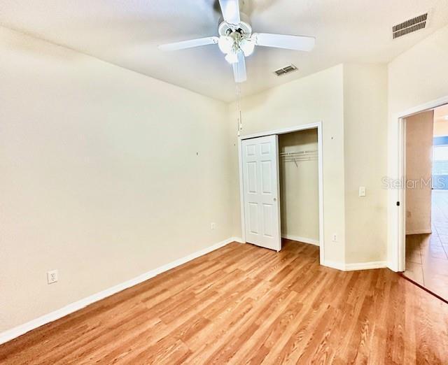 unfurnished bedroom featuring a closet, light hardwood / wood-style flooring, and ceiling fan