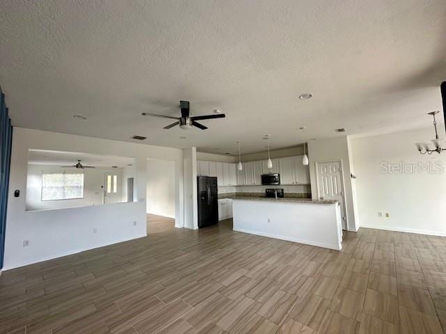 kitchen with black refrigerator, hardwood / wood-style floors, white cabinetry, and hanging light fixtures