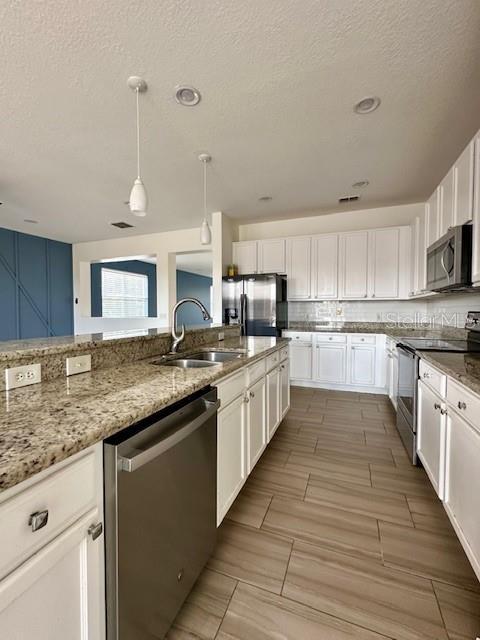 kitchen featuring pendant lighting, sink, white cabinetry, and stainless steel appliances