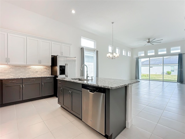 kitchen with ceiling fan with notable chandelier, stainless steel appliances, white cabinetry, and a wealth of natural light