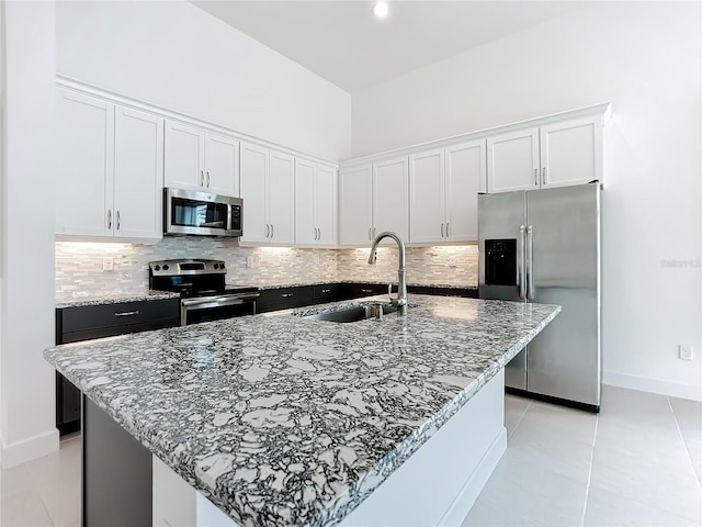 kitchen featuring appliances with stainless steel finishes, white cabinetry, and an island with sink