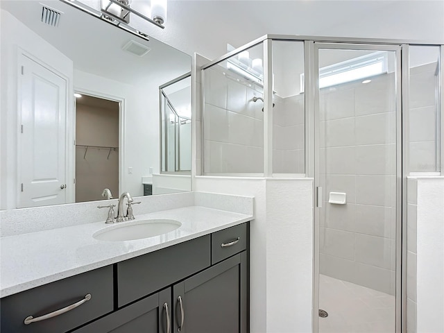 bathroom featuring a shower with door and vanity