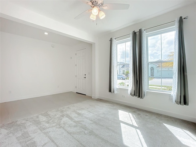 spare room with ceiling fan, light carpet, and a wealth of natural light