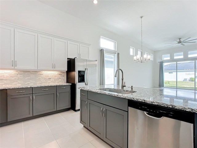 kitchen with white cabinets, ceiling fan with notable chandelier, sink, light stone countertops, and appliances with stainless steel finishes