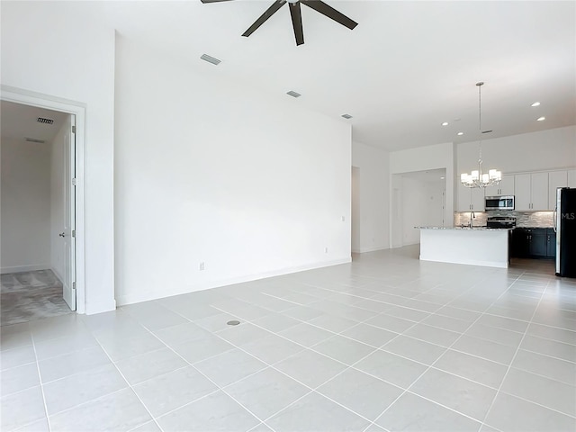 unfurnished living room with light tile patterned floors and ceiling fan with notable chandelier