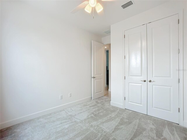 unfurnished bedroom with ceiling fan, a closet, and light colored carpet