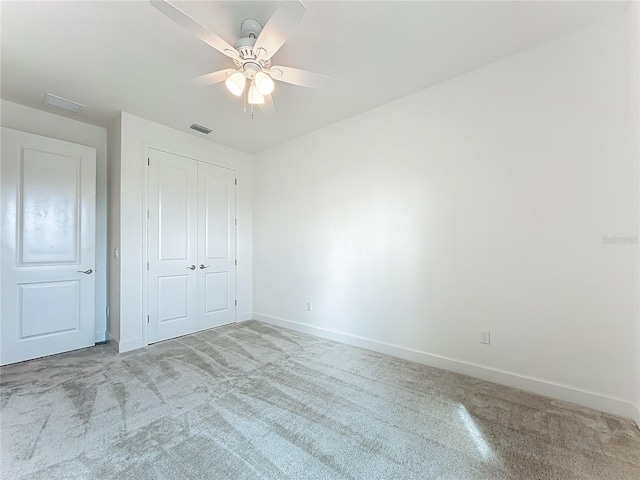 unfurnished bedroom featuring ceiling fan, a closet, and light carpet