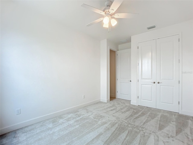 unfurnished bedroom featuring ceiling fan, light carpet, and a closet