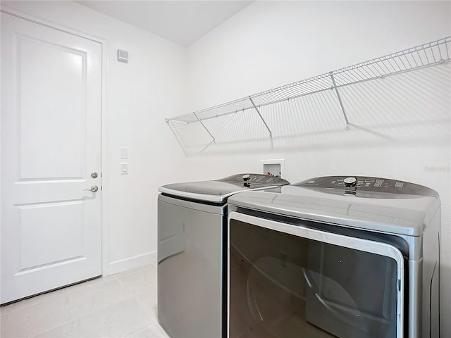 laundry area featuring washing machine and dryer and light tile patterned floors