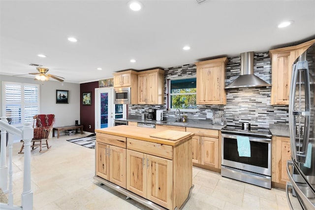 kitchen featuring wall chimney range hood, stainless steel appliances, light brown cabinetry, and tasteful backsplash