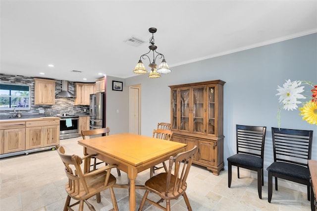 dining room with an inviting chandelier, crown molding, and sink