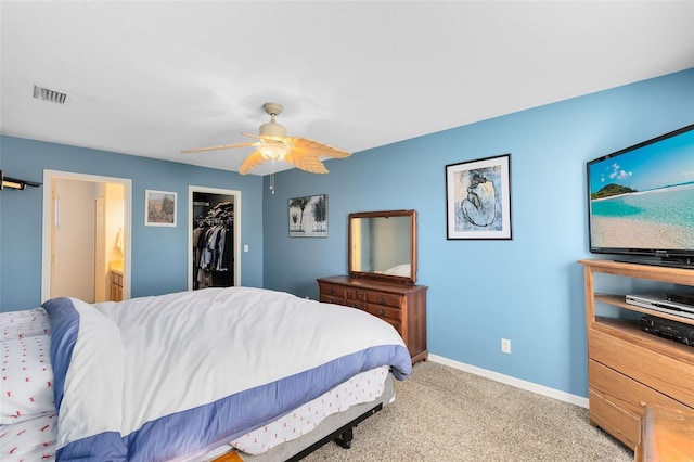 bedroom featuring light carpet, ensuite bath, ceiling fan, a spacious closet, and a closet