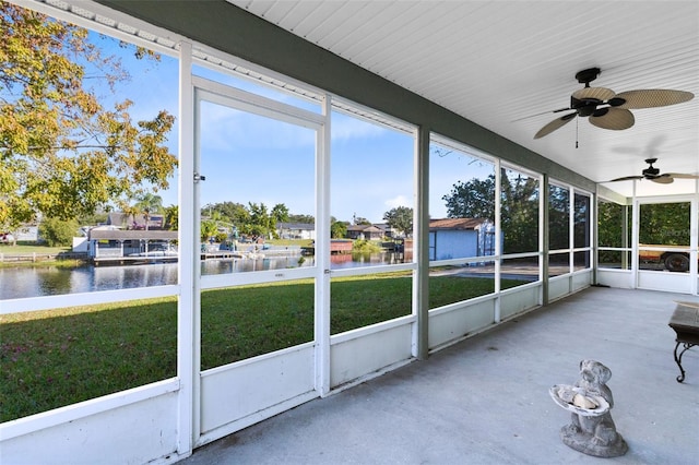 unfurnished sunroom with ceiling fan and a water view