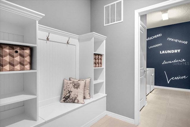 mudroom with washer and clothes dryer and light tile patterned floors