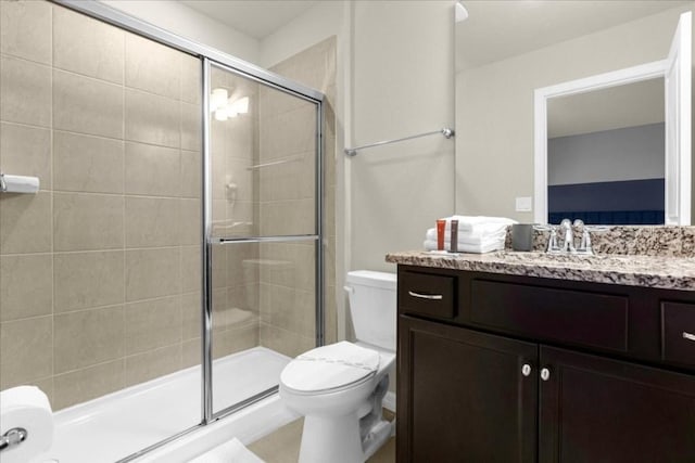 bathroom featuring vanity, toilet, and a shower with door