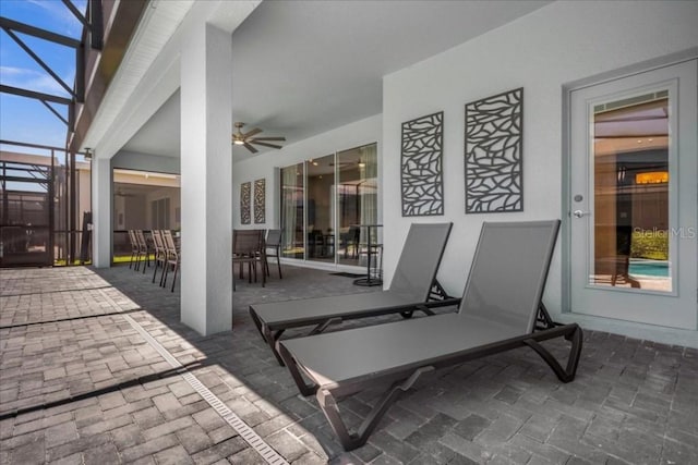 view of patio with glass enclosure and ceiling fan