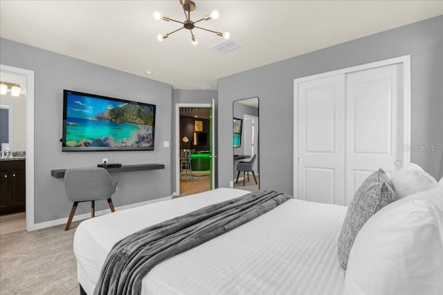 bedroom featuring ensuite bath, light carpet, a closet, and a chandelier