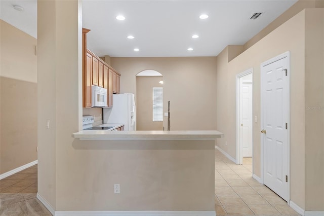 kitchen with white appliances, light brown cabinetry, kitchen peninsula, and light tile patterned floors