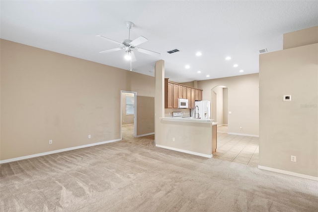 unfurnished living room featuring ceiling fan and light colored carpet