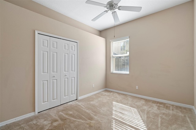 unfurnished bedroom with light colored carpet, ceiling fan, and a closet