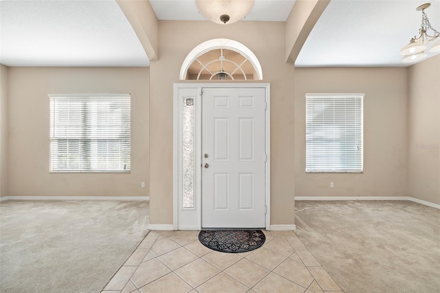 carpeted entryway featuring an inviting chandelier