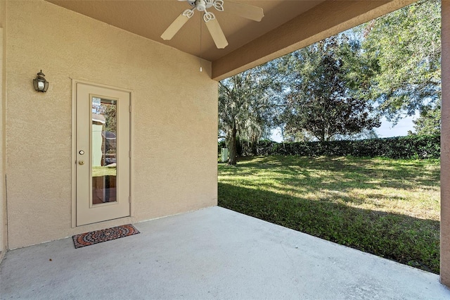 entrance to property featuring a patio, a yard, and ceiling fan