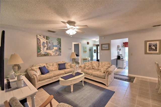 tiled living room with ceiling fan and a textured ceiling