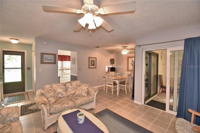 living room featuring ceiling fan, a textured ceiling, and light tile patterned flooring