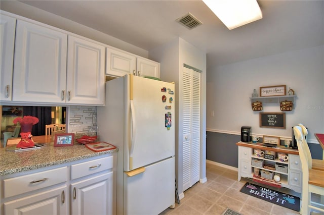 kitchen with white cabinets, light tile patterned flooring, and white fridge