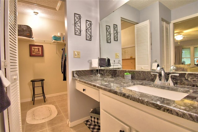 bathroom featuring ceiling fan, vanity, tile patterned flooring, and a textured ceiling