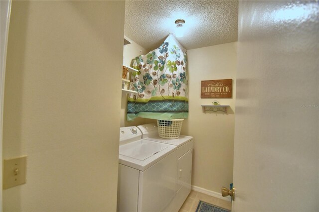 clothes washing area with a textured ceiling, light tile patterned floors, and washing machine and clothes dryer