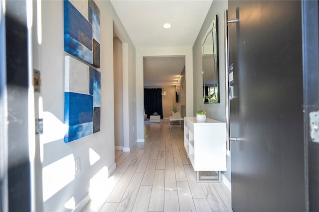 hallway with a textured ceiling and light hardwood / wood-style flooring