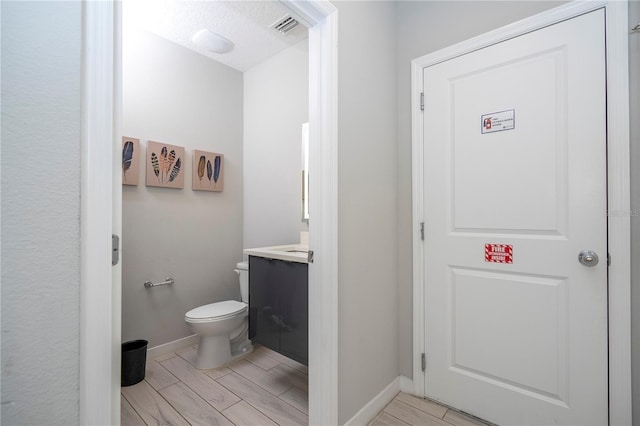 bathroom featuring hardwood / wood-style floors, vanity, a textured ceiling, and toilet