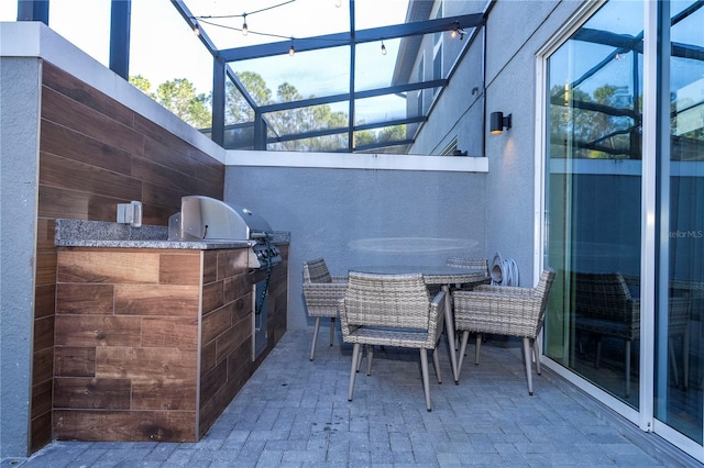 view of patio with an outdoor kitchen, grilling area, and glass enclosure