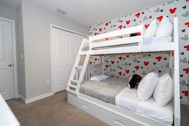 carpeted bedroom featuring a textured ceiling and a closet