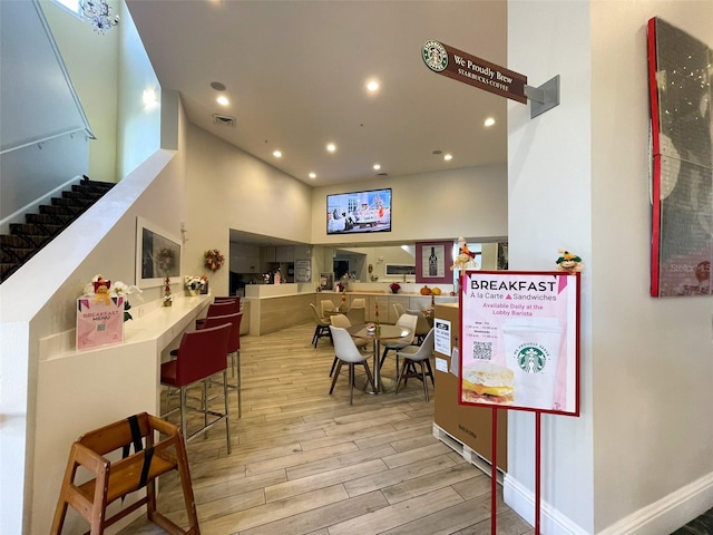 interior space with a towering ceiling and light hardwood / wood-style floors