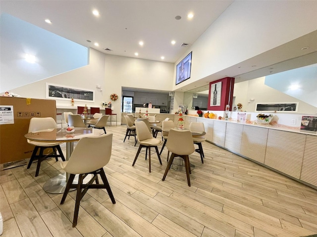 dining space with light wood-type flooring and a high ceiling