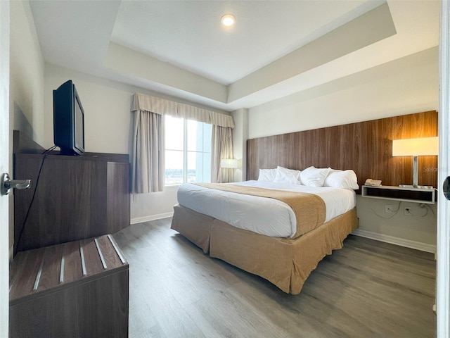 bedroom featuring hardwood / wood-style flooring, wood walls, and a tray ceiling