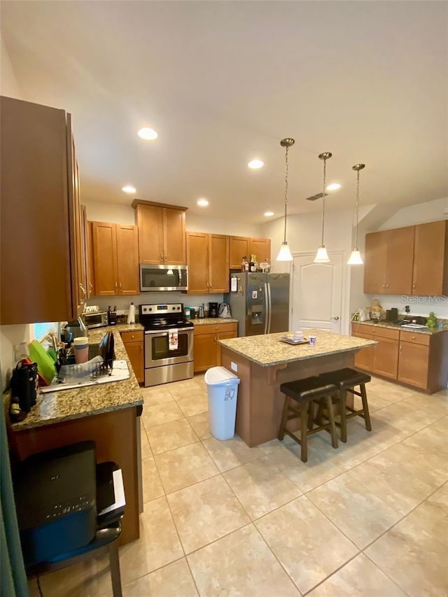 kitchen with a kitchen bar, light stone countertops, stainless steel appliances, light tile patterned floors, and a kitchen island