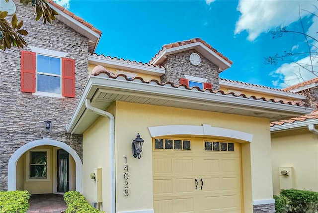 exterior space with stone siding, a tile roof, and stucco siding