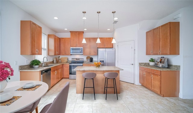 kitchen featuring a sink, visible vents, a kitchen island, appliances with stainless steel finishes, and decorative light fixtures