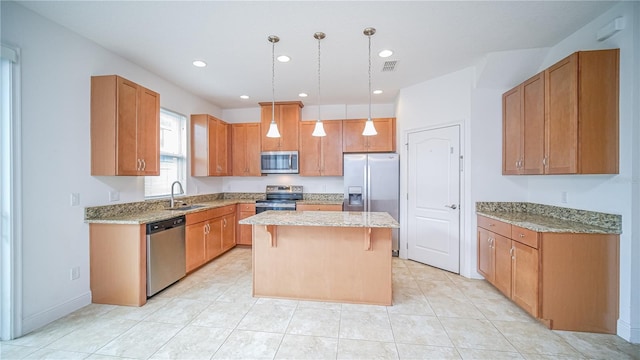 kitchen featuring a kitchen island, a breakfast bar area, hanging light fixtures, stainless steel appliances, and a sink