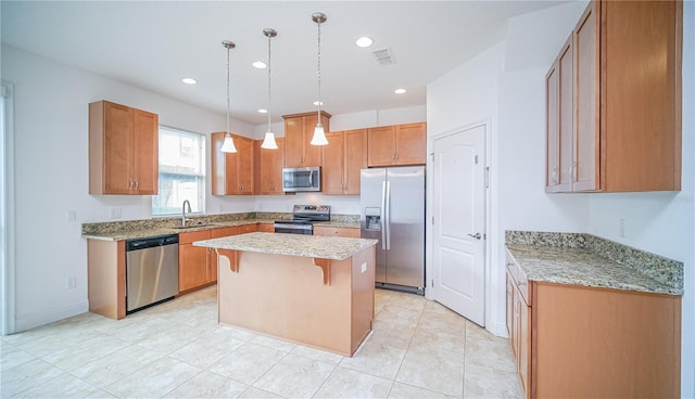 kitchen featuring hanging light fixtures, appliances with stainless steel finishes, a sink, a kitchen island, and a kitchen breakfast bar