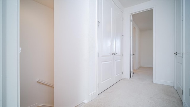 hall featuring light colored carpet and baseboards