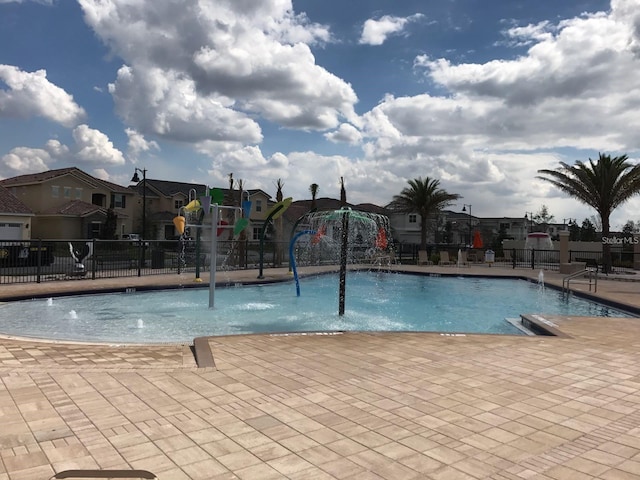 community pool with a residential view, fence, and a patio