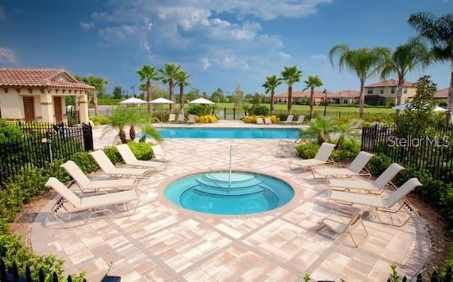 pool with a community hot tub, a patio, and fence