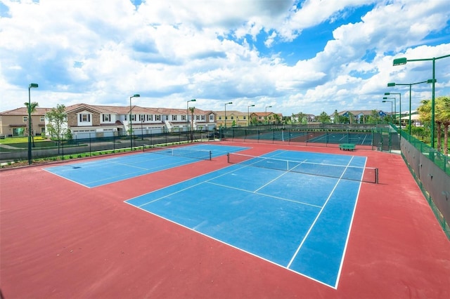 view of tennis court featuring fence and a residential view