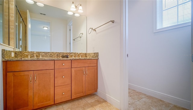 bathroom featuring double vanity, visible vents, a sink, baseboards, and tile patterned floors