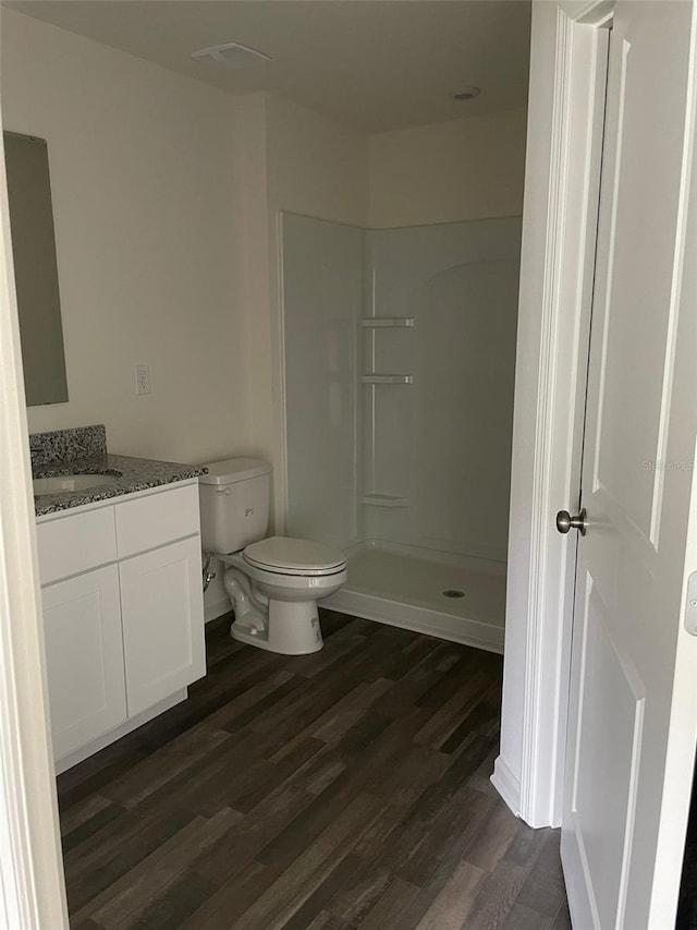 bathroom with a shower, hardwood / wood-style floors, vanity, and toilet